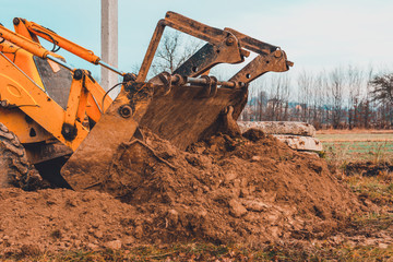 Closeup of a large bucket excavator digging the ground to set the road.