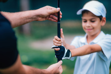 Golf Instructor adjusting young boy’s grip