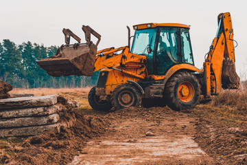 A close-up excavator loads soil into the bucket for further road installation.