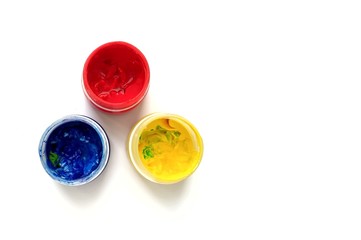 Gouache paints in jars. Bright color. Gouache has already been used, some colors are soiled. Red, yellow, and blue colors in small jars. The view from the top. Horizontal photo with space for text