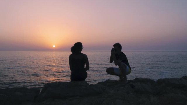 Couple taking a picture, during sunset by the ocean.
