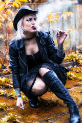 Blonde woman dressed as a cowgirl smoking a cigarette - obrazy, fototapety, plakaty
