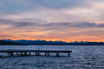 Fototapeta premium Ammersee mit Steg und Bergblick bei Sonnenuntergang / Alpen - Herrsching