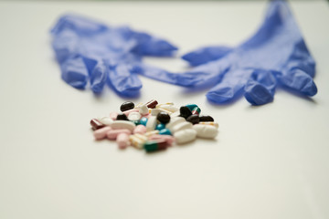 different pills and capsules and a pair of blue latex gloves. Concept of pharmacy, drugs and medicine