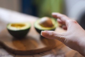 A hand reaches for an avocado