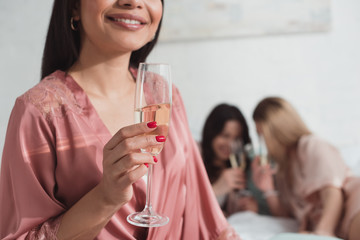 Cropped view of african american girl smiling and holding champagne glass