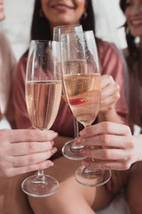 Cropped view of multiethnic women clinking with champagne glasses at bachelorette party