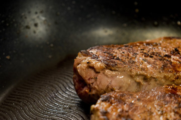 A close up of two organic sirloin grass fed Irish steaks cooking in a pan