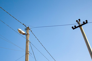 old pole with electric wires and a lamp, next to another pole