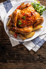 Roasted chicken and american potatoes with chili peppers and herbs - Top of view