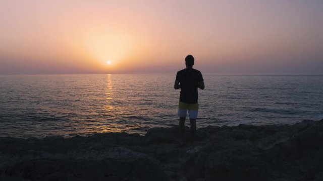Man taking an analog picture at a beautiful sunset over the ocean