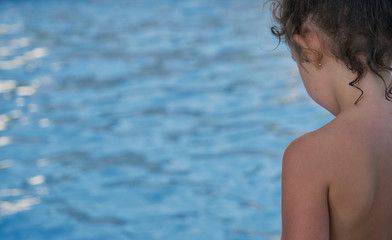 a girl with her back to the edge of an apartment block pool