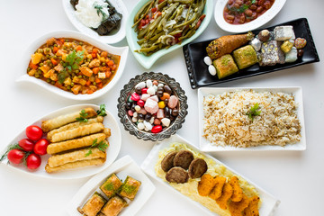 Traditional Turkish dinner table(bayram sofrasi))the End of Ramadan Feast or Sacrifice Feast.Designed feast foods around of copper candy bowl,on the white surface.Top view.
