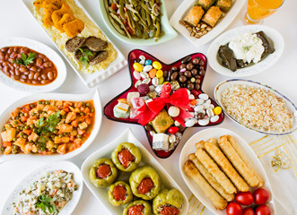 Setting dinner table for feast(bayram sofrasi)with traditional Turkish foods around of star shaped red candy plate on the middle of table.