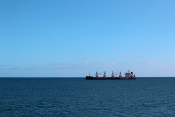 cargo ship going to a harbour in a calm sea with clear sky in summer