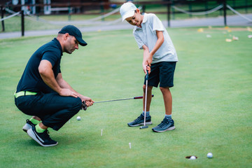 Obraz premium Learning Golf. Boy practicing putting with instructor