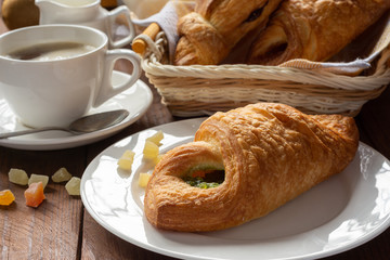 A variety of puff pastry buns with cherries, kiwi, apricot. Rolls, croissants with various fillings. A Cup of coffee with milk, Breakfast. Still-life.
