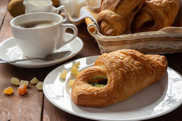 A variety of puff pastry buns with cherries, kiwi, apricot. Rolls, croissants with various fillings. A Cup of coffee with milk, Breakfast. Still-life.