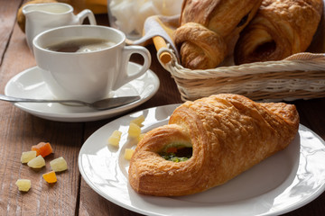 A variety of puff pastry buns with cherries, kiwi, apricot. Rolls, croissants with various fillings. A Cup of coffee with milk, Breakfast. Still-life.