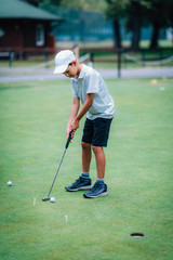 Learning Golf. Boy practicing putting with instructor