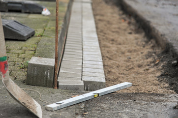 Konzept Krise im Handwerk / Arbeit niedergelegt: Stopp oder Zwangspause auf einer Baustelle mit Wasserwaage, Schaufel und Pflastersteinen - selektiver Fokus, viel Copyspace..