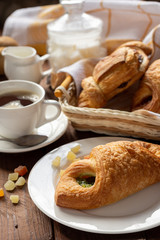 A variety of puff pastry buns with cherries, kiwi, apricot. Rolls, croissants with various fillings. A Cup of coffee with milk, Breakfast. Still-life.