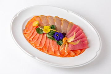 Plate with appetizer of fish and seafood. Sliced salted fish fillet. Smoked salmon, tuna, perch. Banquet festive dishes. Gourmet restaurant menu. White background.