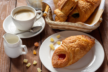 A variety of puff pastry buns with cherries, kiwi, apricot. Rolls, croissants with various fillings. A Cup of coffee with milk, Breakfast. Still-life.