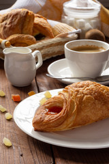 A variety of puff pastry buns with cherries, kiwi, apricot. Rolls, croissants with various fillings. A Cup of coffee with milk, Breakfast. Still-life.