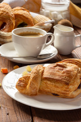 A variety of puff pastry buns with cherries, kiwi, apricot. Rolls, croissants with various fillings. A Cup of coffee with milk, Breakfast. Still-life.