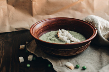 Green cream vegetable soup broccoli, peas, zucchini, spinach with croutons. Delicious vegetarian healthy food.