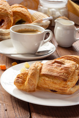 A variety of puff pastry buns with cherries, kiwi, apricot. Rolls, croissants with various fillings. A Cup of coffee with milk, Breakfast. Still-life.