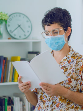 A woman doing research, a young woman reads a book while wearing a mask to avoid contagion, in the background a bookcase with a clock