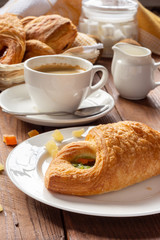 A variety of puff pastry buns with cherries, kiwi, apricot. Rolls, croissants with various fillings. A Cup of coffee with milk, Breakfast. Still-life.