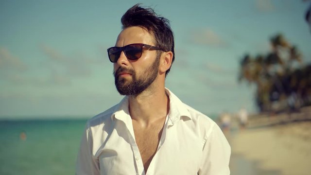 Happy Businessman Enjoying Tropical  Resort Hotel Vacation.Handsome Man Walking On Tropical Beach.Guy Relaxing On Caribbean Sea Beach.Beautiful Tanned Man Healthy Skin Sunbathing Enjoy Ocean Vacation.