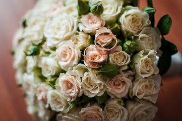 Gold wedding rings on the colorfull bouquet of flowers