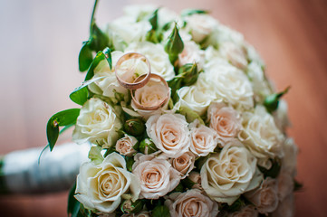 Gold wedding rings on the colorfull bouquet of flowers