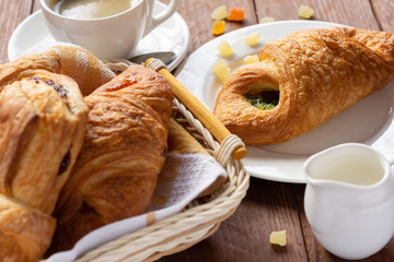 A variety of puff pastry buns with cherries, kiwi, apricot. Rolls, croissants with various fillings. A Cup of coffee with milk, Breakfast. Still-life.