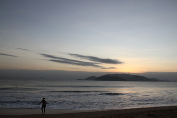 Fototapeta premium Early dawn at sea with an orange stripe from the sun and a silhouette of a man in Vietnam