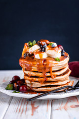 Delicious pancakes with banana, berries, mint and salted caramel in a plate.