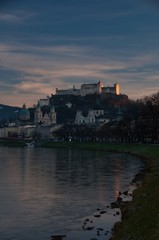 Fototapeta premium die Festung Hohensalzburg in Salzburg gesehen vom Salzachufer bei Sonnenuntergang im Spätherbst goldene Stunde