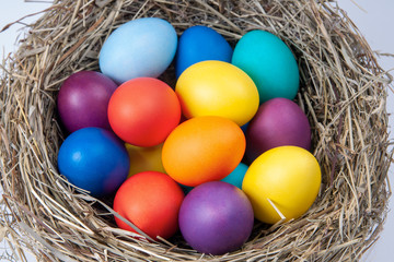 Fototapeta na wymiar Multicolored eggs in nest in the hay. Concept easter.