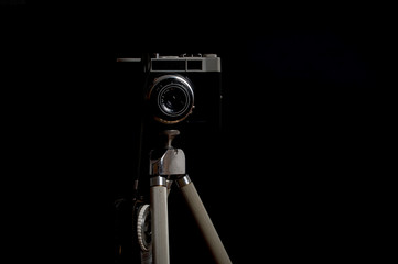 Flat view of an old Russian camera on a metal tripod in front of a black background