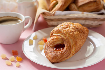 A variety of puff pastry buns with cherries, kiwi, apricot. Rolls, croissants with various fillings. A Cup of coffee with milk, Breakfast. Still-life.