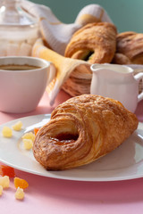 A variety of puff pastry buns with cherries, kiwi, apricot. Rolls, croissants with various fillings. A Cup of coffee with milk, Breakfast. Still-life.