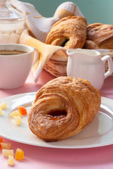 A variety of puff pastry buns with cherries, kiwi, apricot. Rolls, croissants with various fillings. A Cup of coffee with milk, Breakfast. Still-life.