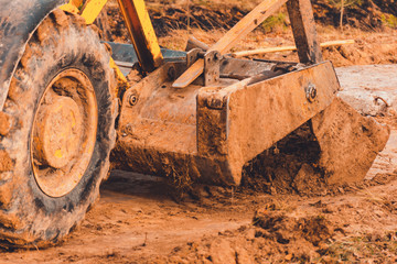 Fototapeta premium The excavator in the countryside moves the concrete slabs for the road.