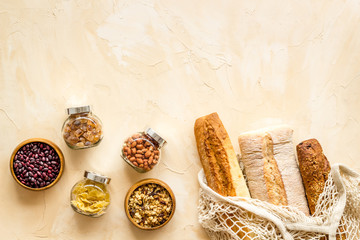 Zero waste food shopping. Cotton bags, glass and wooden jars with groceries. Eco friendly, plastic free flat lay on brown table