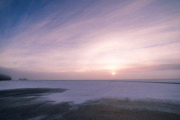 Sun through fog at lake winter morning