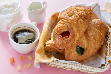 A variety of puff pastry buns with cherries, kiwi, apricot. Rolls, croissants with various fillings. A Cup of coffee with milk, Breakfast. Still-life.